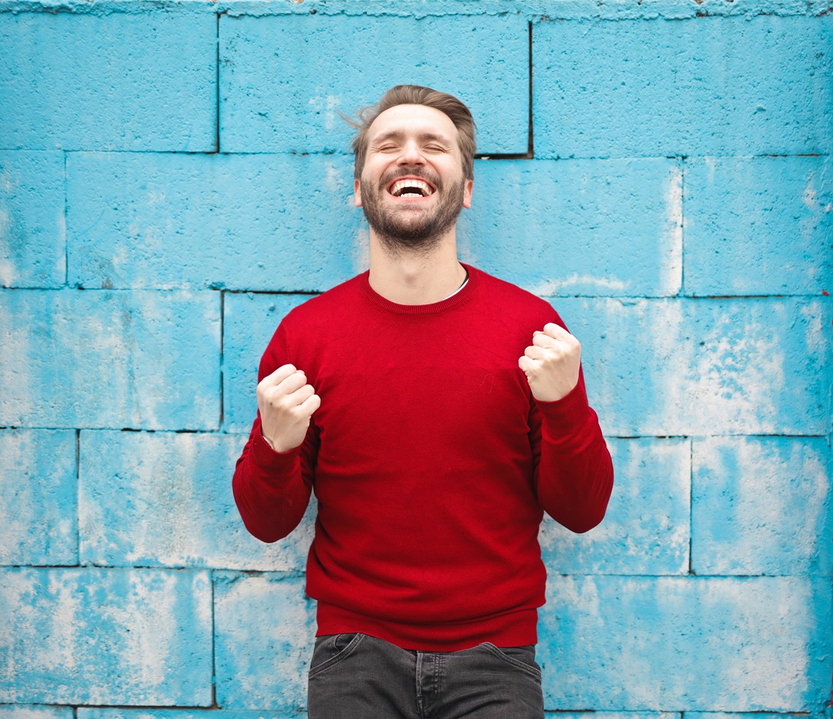 bruce-mars-AndE50aaHn4-unsplash Man in red jumper fist pumping with eyes closed and a huge smile on his face
