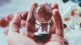 Small glass globe ornament held in someone's hand with a blurred background