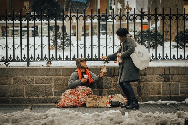homeless Woman giving homeless man help.