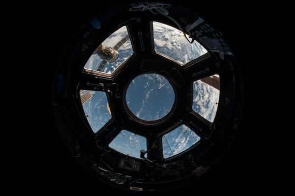 Inside a spaceship looking through a window back towards to Earth.
