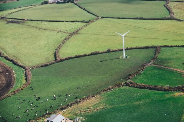 Aerial view of windmill surrounded by green fields.