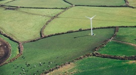 Aerial view of windmill surrounded by green fields.