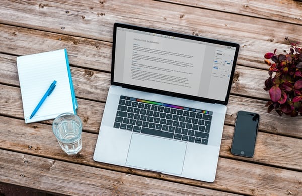 photo-1485988412941-77a35537dae4 Laptop on table next to notepad and pen