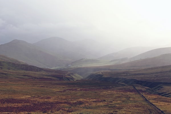 photo-1512664009674-8dc373d31c6a Landscape shot of peatland in a valley, with mountains in the misty background.