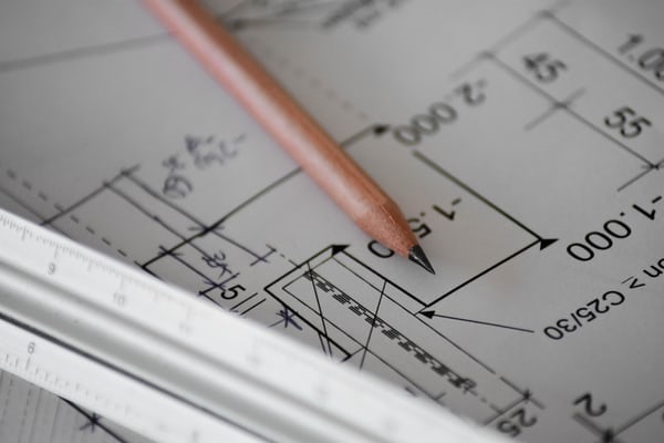 photo-1542621334-a254cf47733d Plans covered by a pencil.
