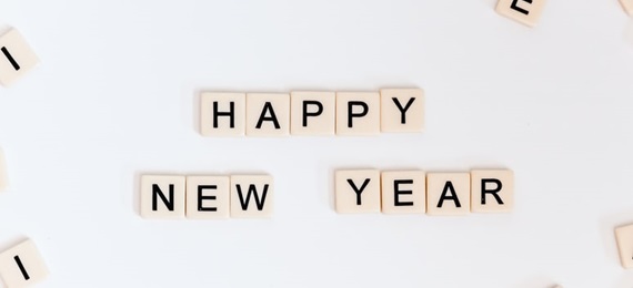 Scrabble tiles on a white background spelling out Happy New Year with some random tiles around the edge