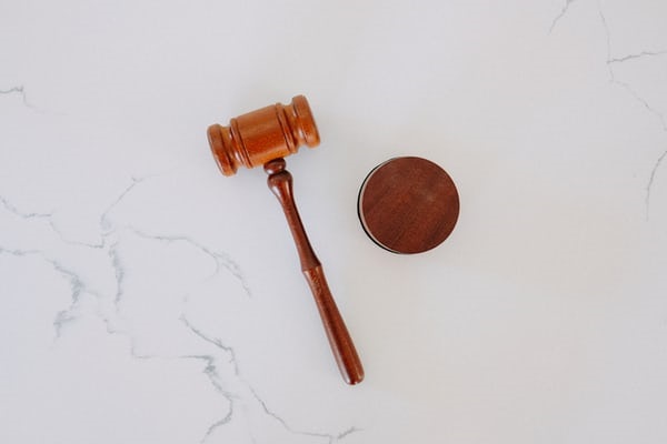 photo-1589391886645-d51941baf7fb Gavel pictured on marble surface.