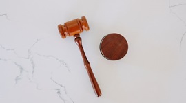 Gavel pictured on marble surface.