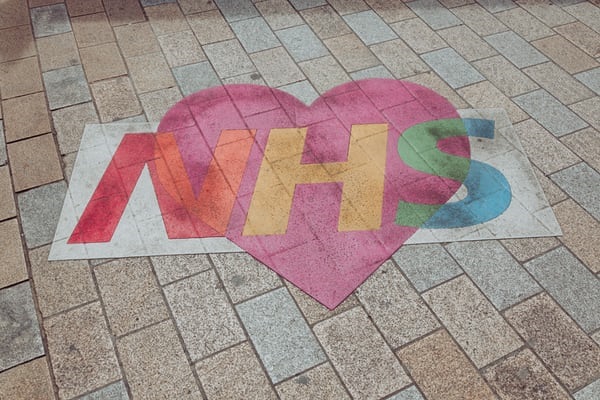 Street art showing the NHS logo in colours and on a heart background.