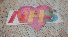 Street art showing the NHS logo in colours and on a heart background.