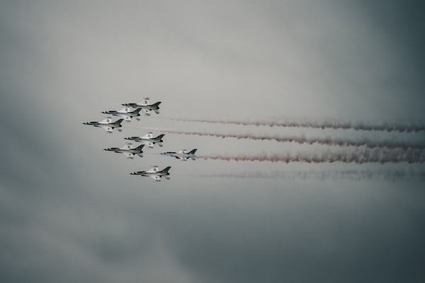 photo-1617689348265-8be393053139 Air force- planes flying through sky leaving trail of smoke in formation.