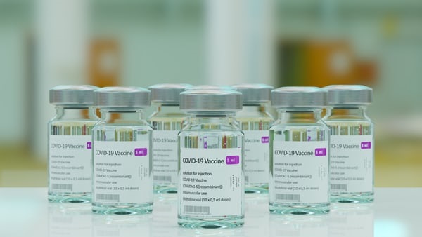 Vials of liquid with stickers on reading 'COVID-19 Vaccine'.