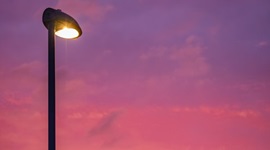 A street lamp switched on against a pink-purple sky.